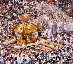 祭りで神輿が担がれ水かけが行われている様子