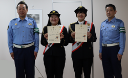 一日警察署長であるガンバレルーヤの2人が委嘱状を掲げる様子